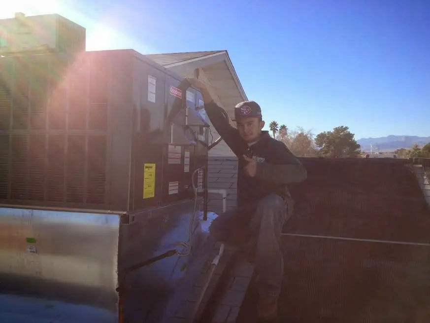 HVAC technician performing Air Duct Repair on a rooftop unit in Mapleton