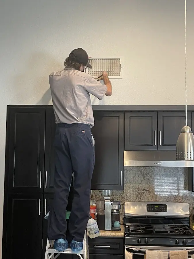 Technician inspecting an air vent during HVAC service in Mapleton